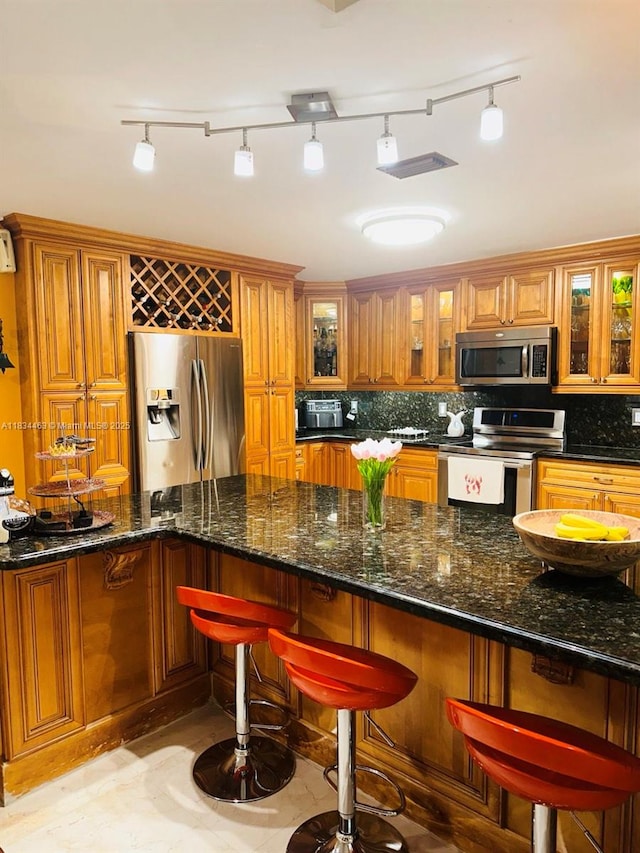 8565 NW 168th Ter, Miami Lakes, FL 33016 - kitchen featuring appliances with stainless steel finishes, brown cabinetry, tasteful backsplash, and glass insert cabinets