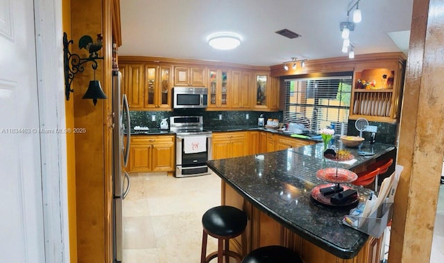 8565 NW 168th Ter, Miami Lakes, FL 33016 - kitchen with appliances with stainless steel finishes, a peninsula, a breakfast bar area, decorative backsplash, and glass insert cabinets