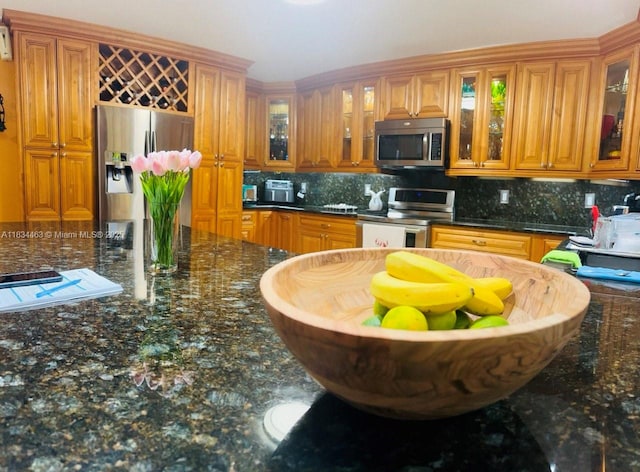 8565 NW 168th Ter, Miami Lakes, FL 33016 - kitchen with appliances with stainless steel finishes, decorative backsplash, brown cabinets, glass insert cabinets, and dark stone countertops