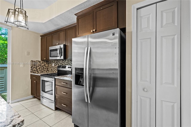 604 SW 107th Ave Unit 706, Pembroke Pines, FL 33025 - kitchen with stainless steel appliances, light tile patterned floors, decorative backsplash, light stone countertops, and dark brown cabinetry
