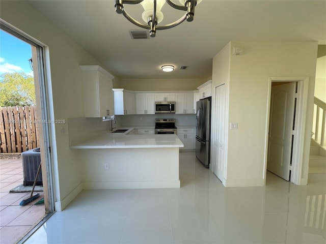 7317 NW 174th Ter Unit 102, Hialeah, FL 33015 - kitchen with appliances with stainless steel finishes, a peninsula, light countertops, white cabinets, and a chandelier