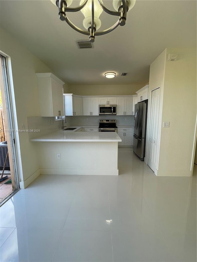 7317 NW 174th Ter Unit 102, Hialeah, FL 33015 - kitchen featuring appliances with stainless steel finishes, light countertops, a peninsula, and a chandelier