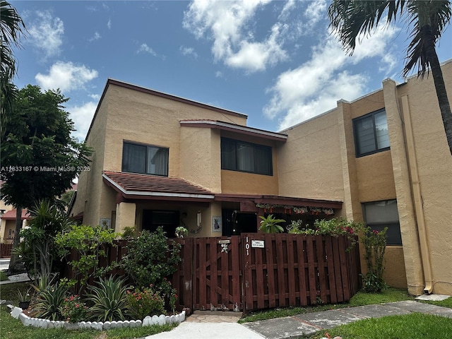 311 W Park Dr Unit 101-13, Miami, FL 33172 - view of front of home featuring stucco siding, a fenced front yard, and a gate