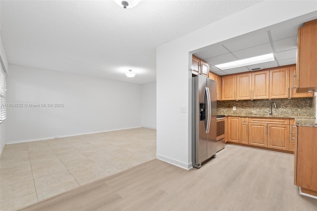 800 SW 131st Ave Unit 406F, Pembroke Pines, FL 33027 - kitchen featuring stainless steel refrigerator with ice dispenser, decorative backsplash, stone countertops, light wood-style flooring, and stove