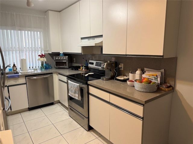 17048 NW 66th Ct, Miami Lakes, FL 33015 - kitchen with stainless steel appliances, under cabinet range hood, white cabinets, light tile patterned floors, and dark countertops