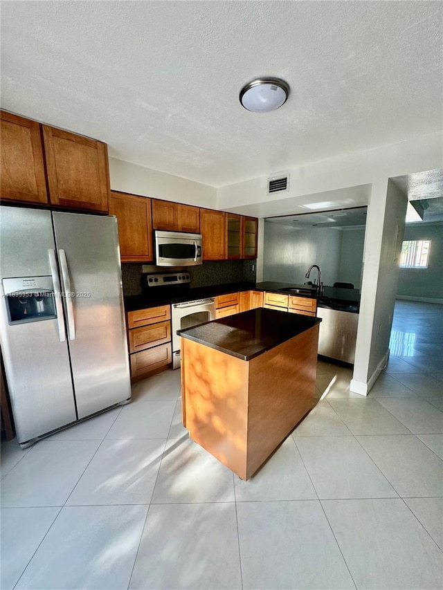 8240 SW 149th Ct Unit 7-202, Miami, FL 33193 - kitchen featuring stainless steel appliances, dark countertops, tasteful backsplash, a textured ceiling, and a center island