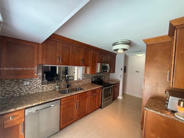 14135 SW 100th Ln, Miami, FL 33186 - kitchen featuring appliances with stainless steel finishes, backsplash, stone counters, brown cabinetry, and light tile patterned flooring