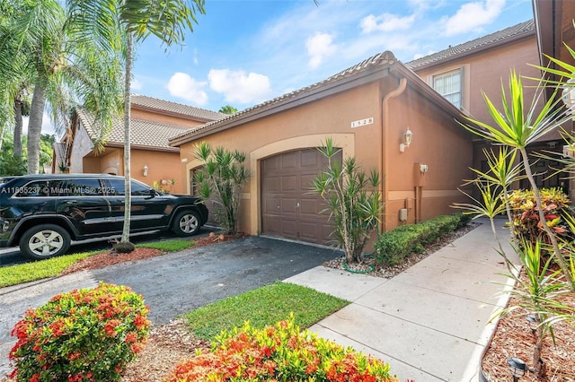 1528 Veracruz Ln Unit 4-3, Weston, FL 33327 - view of home's exterior with an attached garage, asphalt driveway, and stucco siding
