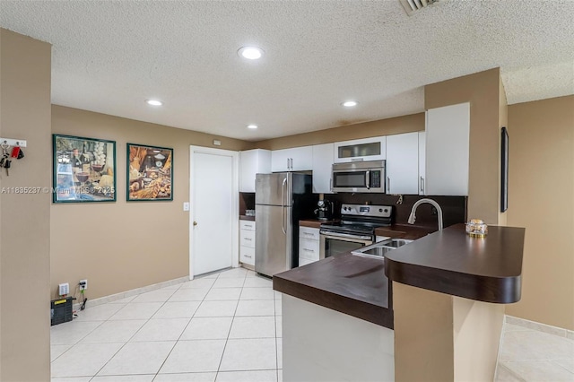 1528 Veracruz Ln Unit 4-3, Weston, FL 33327 - kitchen featuring stainless steel appliances, dark countertops, a peninsula, a textured ceiling, and glass insert cabinets