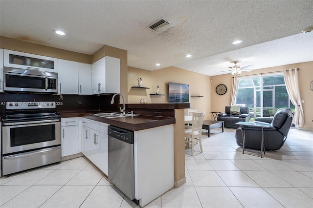 1528 Veracruz Ln Unit 4-3, Weston, FL 33327 - kitchen featuring appliances with stainless steel finishes, a peninsula, dark countertops, open floor plan, and light tile patterned floors