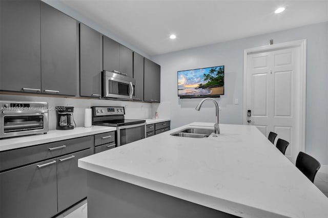 14646 SW 13th St, Pembroke Pines, FL 33027 - kitchen featuring appliances with stainless steel finishes, gray cabinets, recessed lighting, a breakfast bar area, and a center island with sink