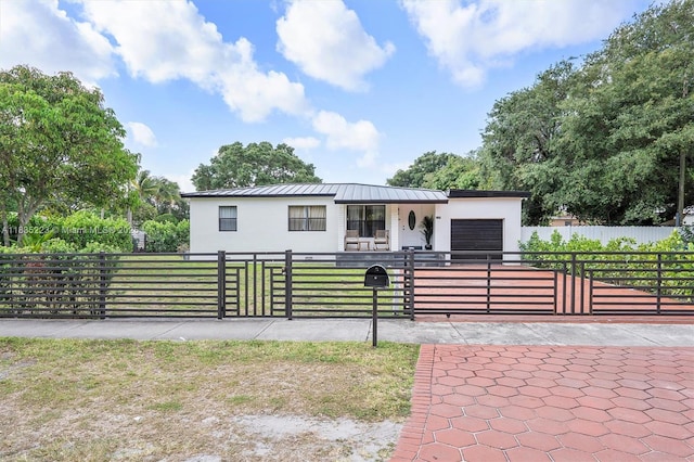 1100 NW 151st St, Miami, FL 33169 - view of front of house with a garage, a fenced front yard, stucco siding, a standing seam roof, and a metal roof