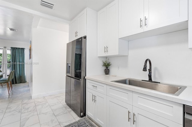 1100 NW 151st St, Miami, FL 33169 - kitchen featuring stainless steel fridge, light marble finish flooring, light countertops, and white cabinetry