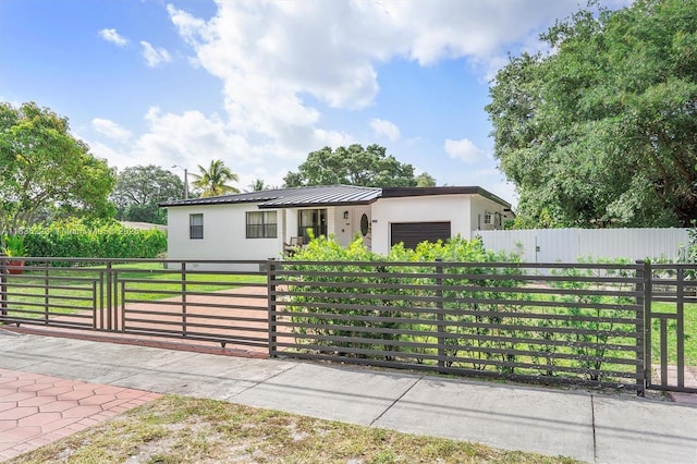 1100 NW 151st St, Miami, FL 33169 - view of front of house featuring a fenced front yard, an attached garage, stucco siding, and a metal roof