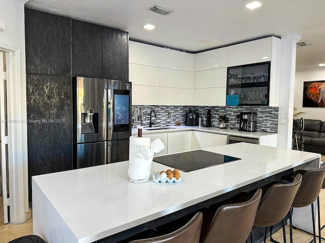 7427 NW 113th Path, Doral, FL 33178 - kitchen with refrigerator with ice dispenser, modern cabinets, black electric cooktop, decorative backsplash, and a kitchen breakfast bar