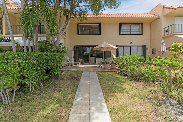 1426 NE 105th St Unit D9, Miami Shores, FL 33138 - back of house with a tile roof, stucco siding, a patio, and a lawn
