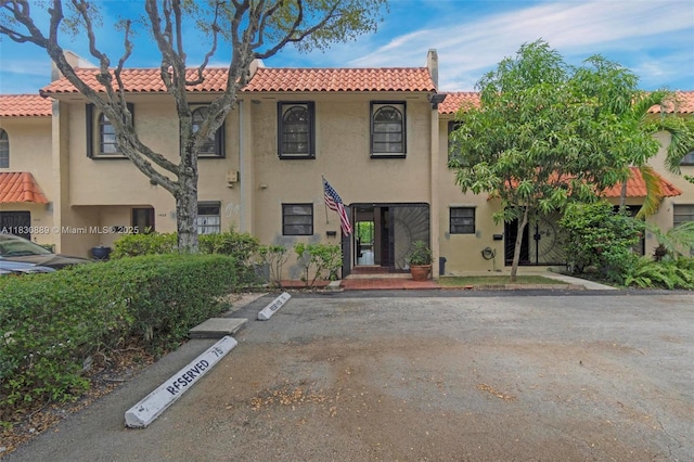 1426 NE 105th St Unit D9, Miami Shores, FL 33138 - view of front of property featuring stucco siding, a tiled roof, uncovered parking, and a chimney