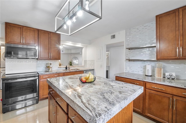 1706 Hammock Blvd Unit 110, Coconut Creek, FL 33063 - kitchen featuring stainless steel appliances, tasteful backsplash, a kitchen island, and brown cabinetry
