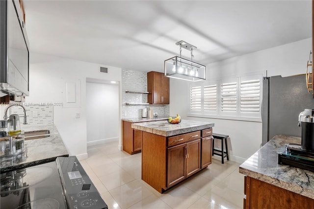 1706 Hammock Blvd Unit 110, Coconut Creek, FL 33063 - kitchen featuring freestanding refrigerator, backsplash, brown cabinetry, and a kitchen island