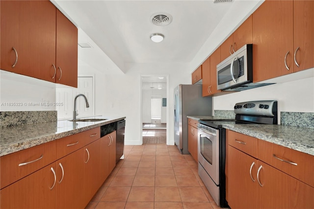 15831 Palmetto Club Dr, Miami, FL 33157 - kitchen featuring appliances with stainless steel finishes, light tile patterned floors, brown cabinets, and light stone countertops