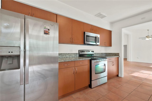15831 Palmetto Club Dr, Miami, FL 33157 - kitchen featuring appliances with stainless steel finishes, light tile patterned floors, light stone countertops, a ceiling fan, and brown cabinetry