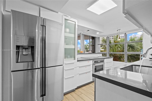3530 Mystic Pointe Dr Unit 309, Aventura, FL 33180 - kitchen featuring stainless steel appliances, white cabinetry, light wood-style flooring, modern cabinets, and glass insert cabinets