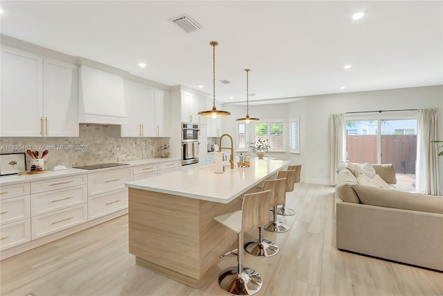 14751 SW 23rd St Unit 14751, Miami, FL 33185 - kitchen featuring stainless steel double oven, light wood-type flooring, a kitchen breakfast bar, open floor plan, and backsplash