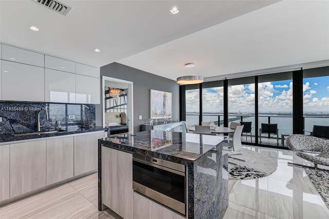 3131 NE 7th Ave Unit 4001, Miami, FL 33137 - kitchen featuring modern cabinets, dark stone countertops, backsplash, expansive windows, and a kitchen island