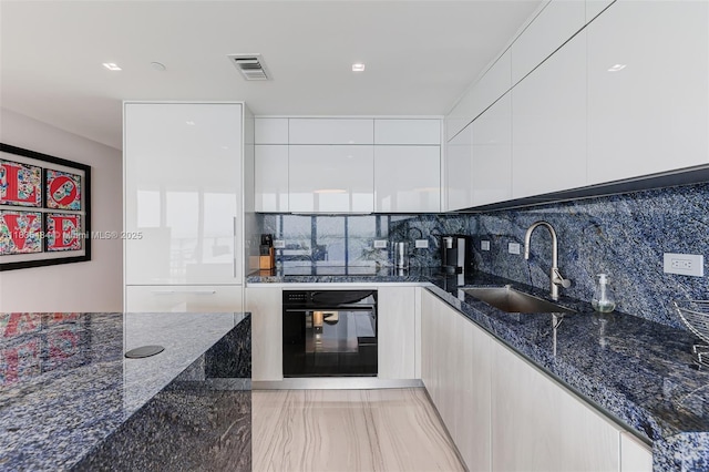 3131 NE 7th Ave Unit 4001, Miami, FL 33137 - kitchen featuring black oven, modern cabinets, white cabinets, and dark stone counters