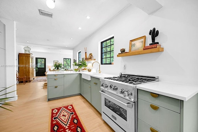 135 NE 87th St, El Portal, FL 33138 - kitchen featuring high end stainless steel range oven, a peninsula, healthy amount of natural light, gray cabinets, and recessed lighting