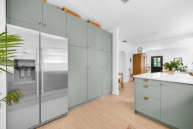 135 NE 87th St, El Portal, FL 33138 - kitchen with stainless steel fridge with ice dispenser, arched walkways, light wood finished floors, gray cabinets, and light countertops