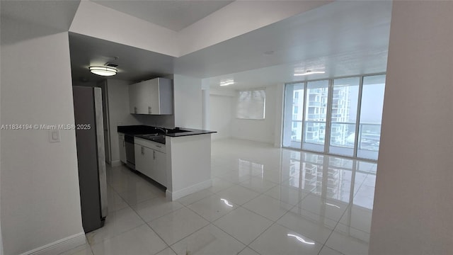 1871 NW S River Dr Unit 1506, Miami, FL 33125 - kitchen with dark countertops, light tile patterned flooring, stainless steel appliances, white cabinetry, and open floor plan