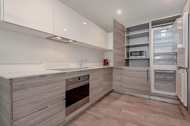 777 N Ocean Dr Unit N401, Hollywood, FL 33019 - kitchen with appliances with stainless steel finishes, modern cabinets, light countertops, exhaust hood, and white cabinets