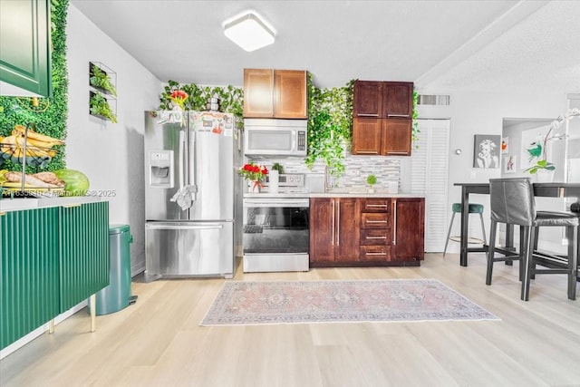 1890 W 56th St Unit 1411, Hialeah, FL 33012 - kitchen featuring appliances with stainless steel finishes, light wood-style floors, tasteful backsplash, and light countertops