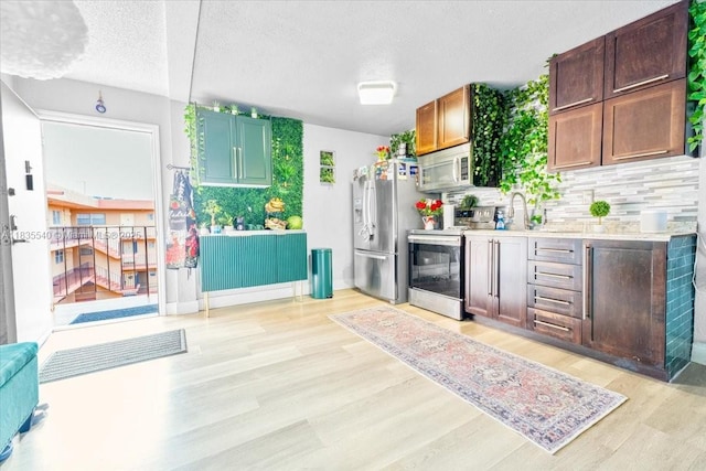 1890 W 56th St Unit 1411, Hialeah, FL 33012 - kitchen with appliances with stainless steel finishes, backsplash, light wood-style flooring, a textured ceiling, and light countertops
