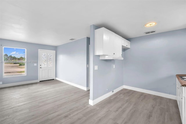 1408 9th St, West Palm Beach, FL 33401 - kitchen with light wood-type flooring and white cabinetry