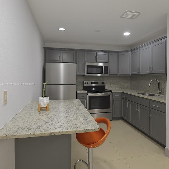 1320 NW 179th Ter, Miami Gardens, FL 33169 - kitchen featuring appliances with stainless steel finishes, gray cabinetry, light stone counters, light tile patterned floors, and recessed lighting