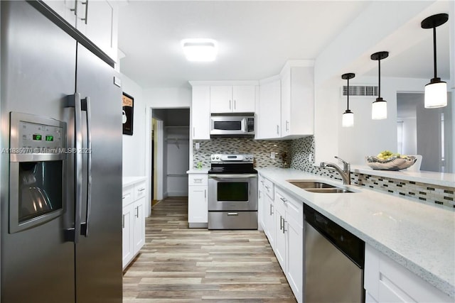 7051 SW 29th St, Miramar, FL 33023 - kitchen featuring stainless steel appliances, backsplash, light wood finished floors, and white cabinets