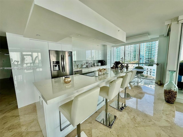 16400 Collins Ave Unit 841, Sunny Isles Beach, FL 33160 - kitchen featuring stainless steel appliances, white cabinetry, light countertops, a breakfast bar, and a center island