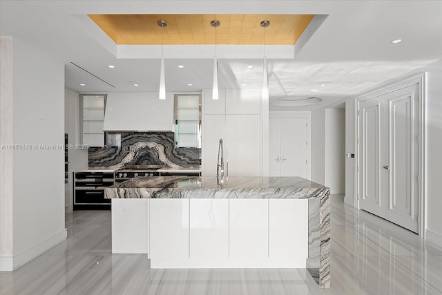 17901 S Collins Ave Unit 1506, Sunny Isles Beach, FL 33160 - kitchen featuring a raised ceiling, light stone countertops, custom range hood, a large island with sink, and tasteful backsplash