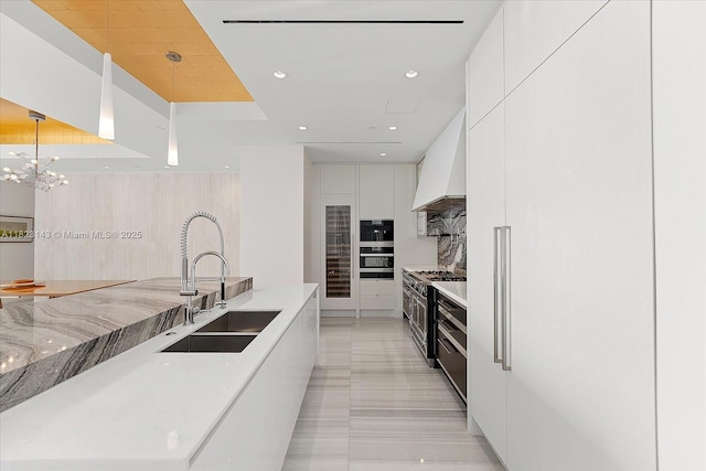 17901 S Collins Ave Unit 1506, Sunny Isles Beach, FL 33160 - kitchen with modern cabinets, premium range hood, white cabinetry, appliances with stainless steel finishes, and a chandelier