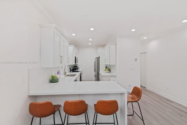 1941 NW 151st St, Miami Gardens, FL 33054 - kitchen with a breakfast bar, appliances with stainless steel finishes, light countertops, white cabinets, and recessed lighting