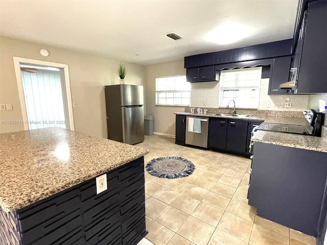 1148 N Singleton Ave, Titusville, FL 32796 - kitchen with stainless steel appliances, light tile patterned floors, light stone countertops, and dark cabinetry