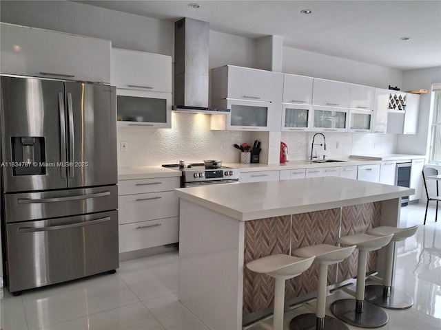 5490 NW 113th Ct, Doral, FL 33178 - kitchen featuring appliances with stainless steel finishes, wall chimney range hood, a breakfast bar, decorative backsplash, and white cabinetry