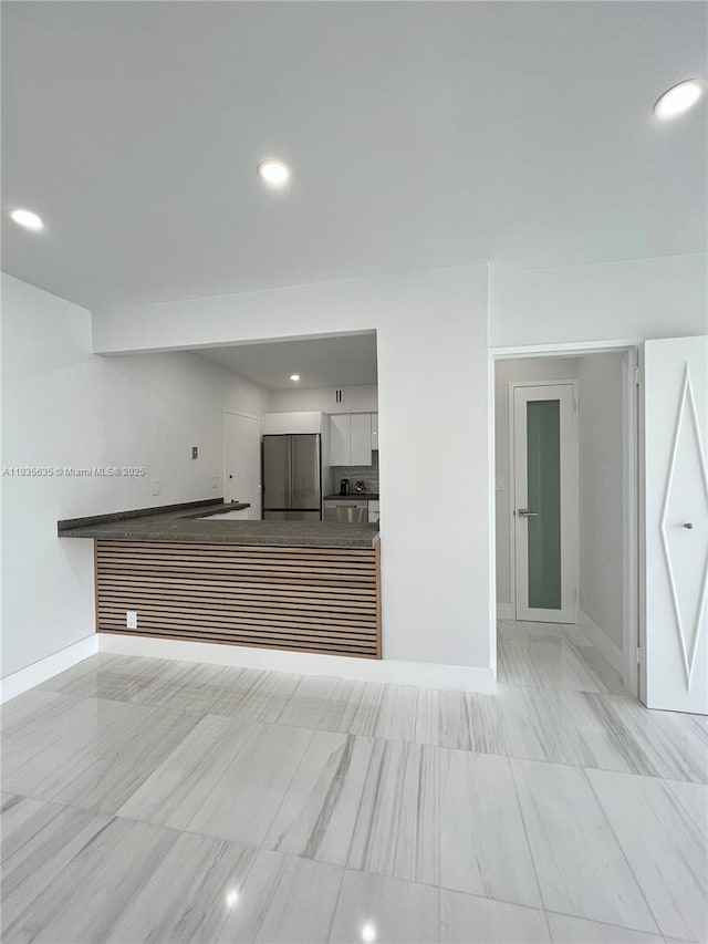 5700 Collins Ave Unit 16B, Miami Beach, FL 33140 - kitchen with stainless steel fridge, white cabinets, and recessed lighting