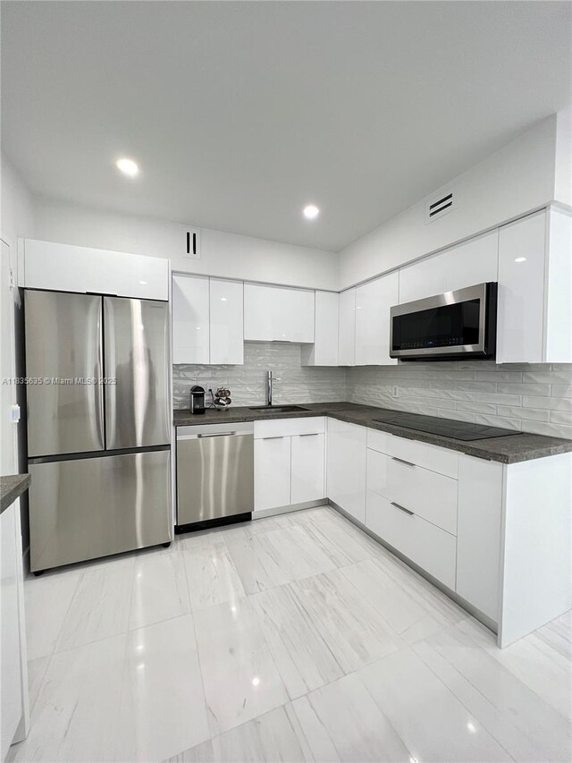 5700 Collins Ave Unit 16B, Miami Beach, FL 33140 - kitchen featuring appliances with stainless steel finishes, modern cabinets, dark countertops, white cabinets, and decorative backsplash