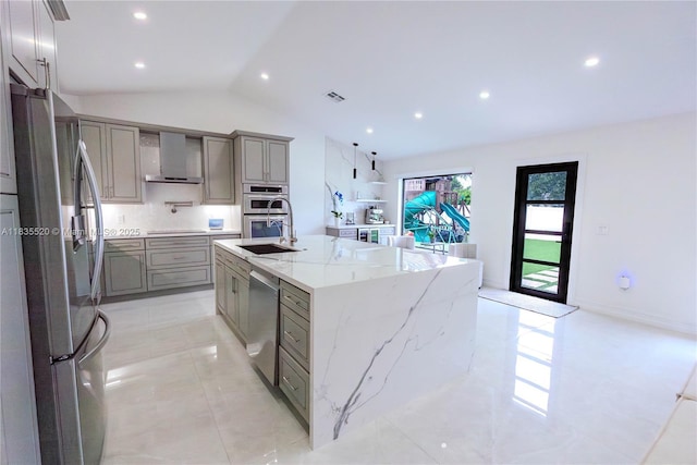 1149 SE Sandia Dr, Port St Lucie, FL 34983 - kitchen featuring appliances with stainless steel finishes, gray cabinetry, wall chimney exhaust hood, lofted ceiling, and a kitchen island with sink