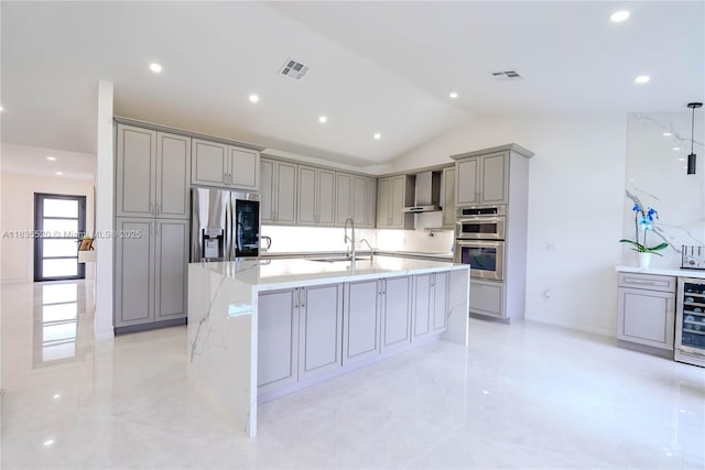 1149 SE Sandia Dr, Port St Lucie, FL 34983 - kitchen with gray cabinetry, appliances with stainless steel finishes, vaulted ceiling, wall chimney range hood, and a large island with sink