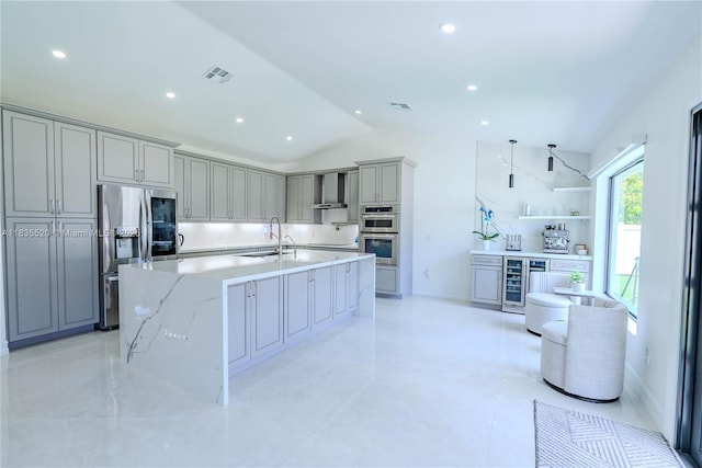 1149 SE Sandia Dr, Port St Lucie, FL 34983 - kitchen featuring appliances with stainless steel finishes, gray cabinetry, wall chimney exhaust hood, vaulted ceiling, and wine cooler