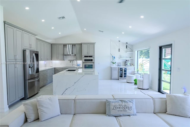 1149 SE Sandia Dr, Port St Lucie, FL 34983 - kitchen featuring stainless steel appliances, gray cabinets, wall chimney range hood, lofted ceiling, and wine cooler